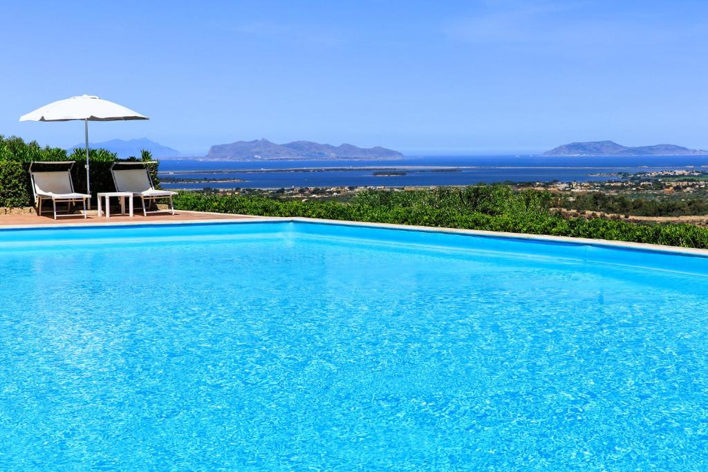 马尔萨拉Hotel Baglio Oneto dei Principi di San Lorenzo - Luxury Wine Resort的一个带两把椅子和遮阳伞的大型游泳池