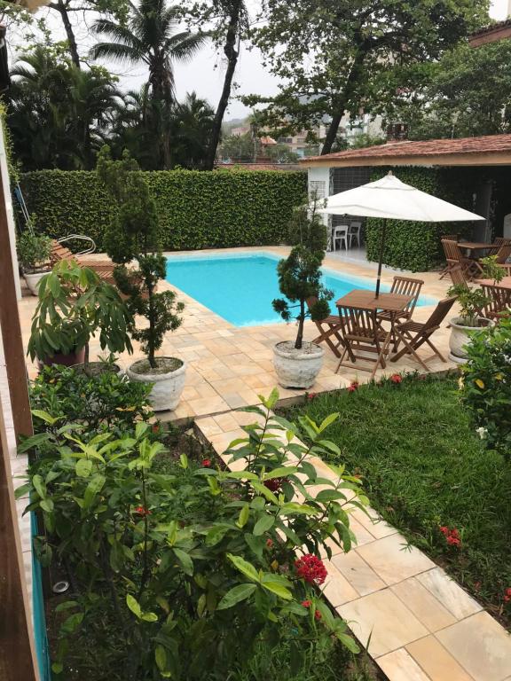 瓜鲁雅Santa Cecília Pousada的后院设有游泳池、桌子和椅子
