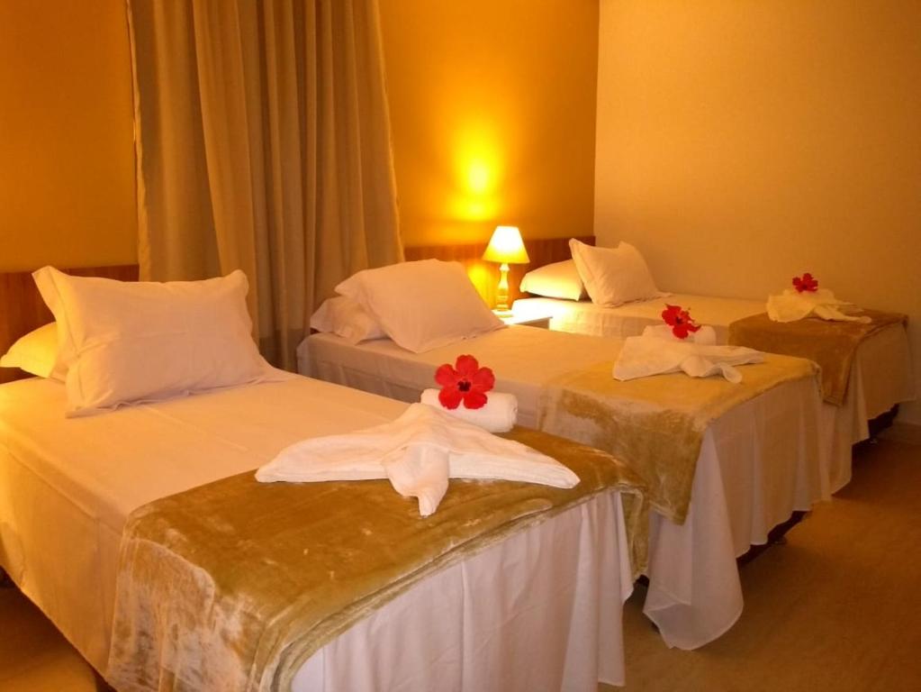 费尔南多 - 迪诺罗尼亚Pousada Aconchego Noronha的酒店内有三张床,上面有红色的鲜花