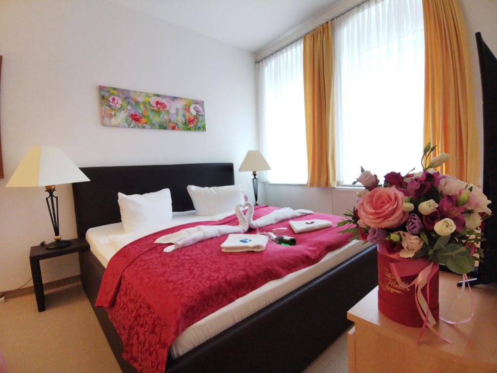 奥泊维森塔尔菲希特尔贝格山景公寓的一间卧室配有一张带红色毯子和鲜花的床