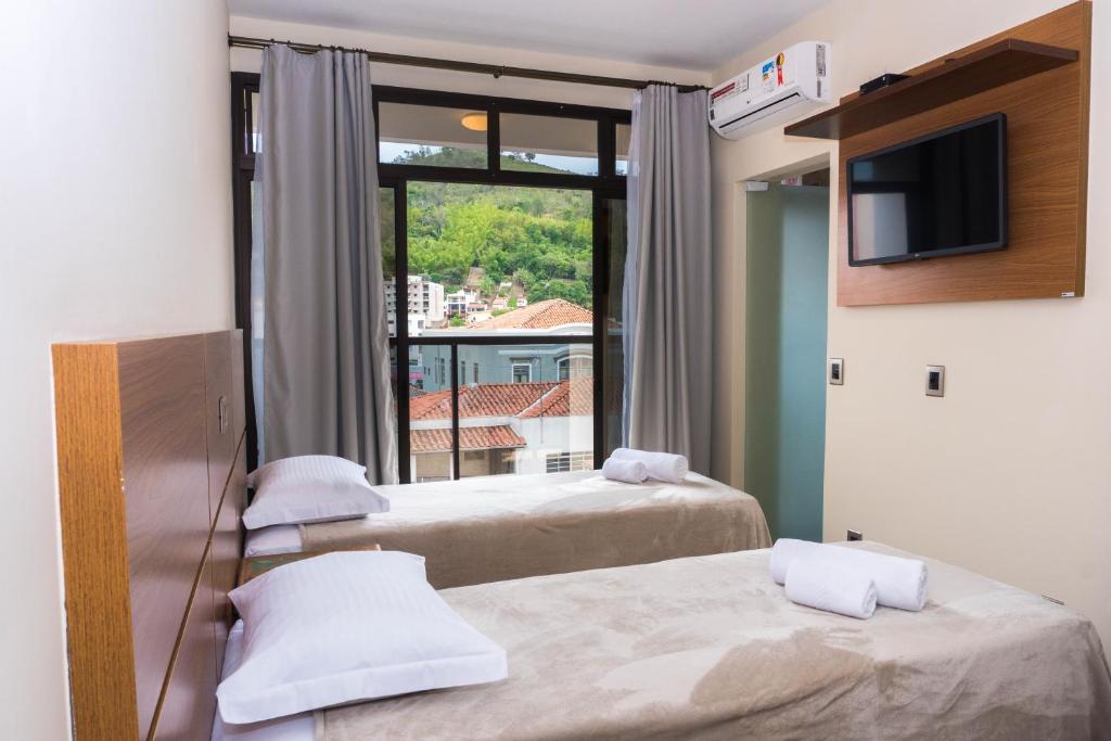 索科罗Hotel Casa Alfredo的客房设有两张床、一台电视和一扇窗户。