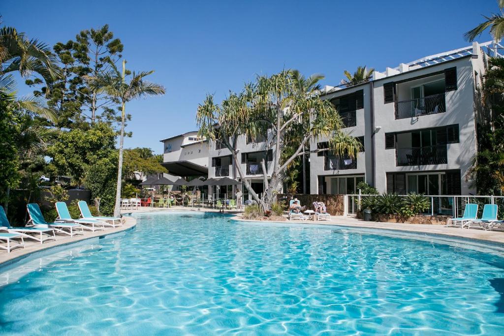 努萨角诺萨蓝色度假酒店的一座带椅子的游泳池以及一座建筑