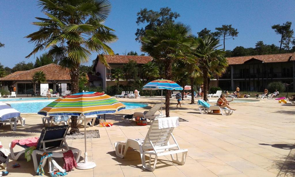 翁德尔T3 Soleil Ondres plages avec piscine et Tennis的一组椅子和遮阳伞,位于游泳池旁