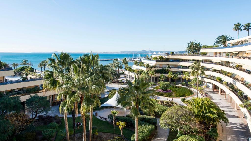 圣罗兰度瓦圣洛朗港尼斯假日酒店的享有棕榈树和海洋度假村的空中景致