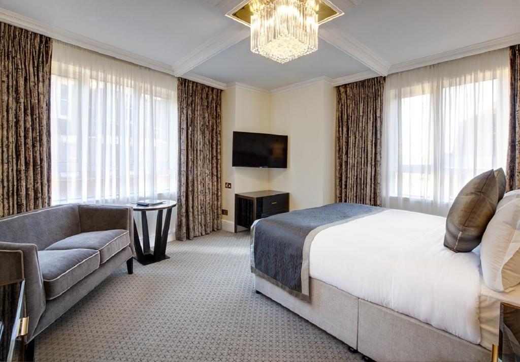 伦敦The Rathbone Hotel, Fitzrovia的一间卧室配有一张床、一张沙发和一台电视
