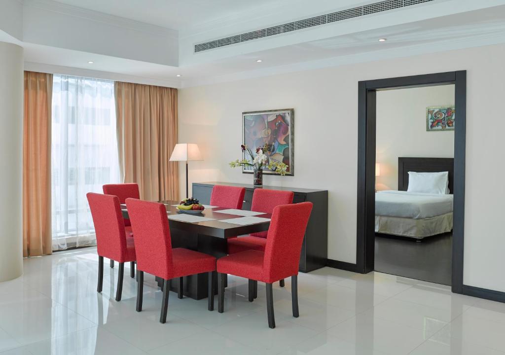 麦纳麦Tulip Hotel & Suites的一间带桌子和红色椅子的用餐室
