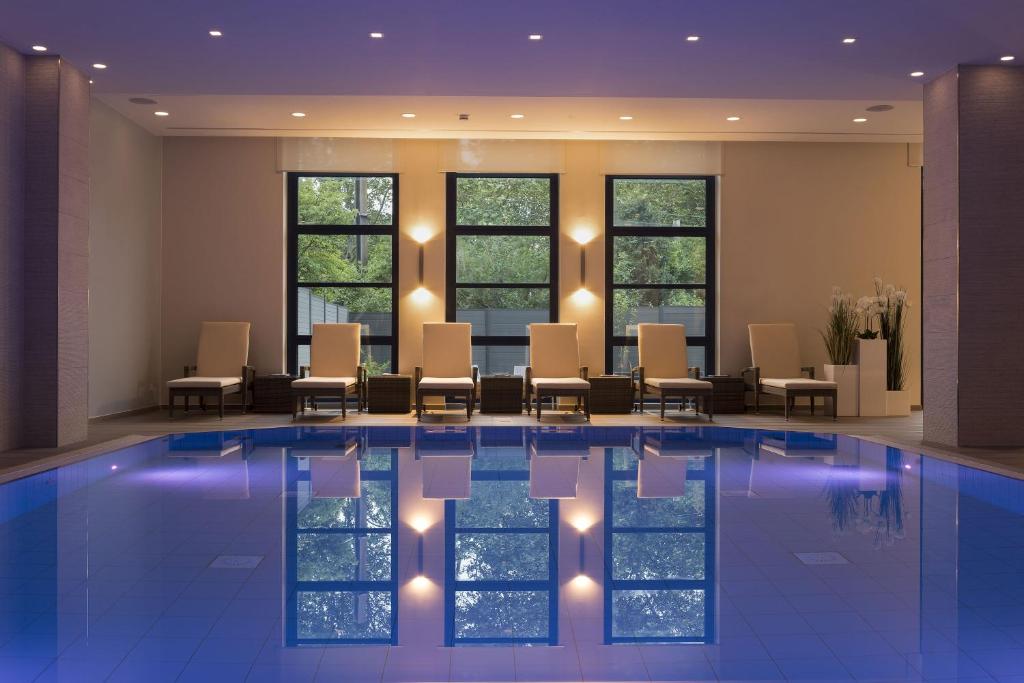 波恩玛丽蒂姆波恩酒店的酒店大堂设有游泳池、椅子和窗户