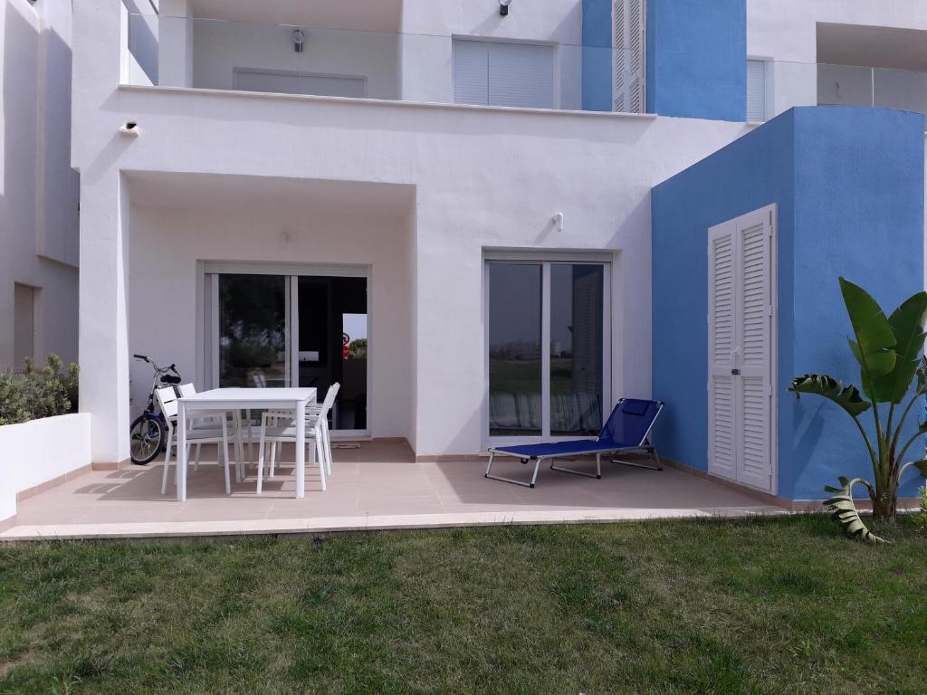 罗尔丹Las Terrazas Golf Resort Rental的白色和蓝色的房子,配有桌子和椅子