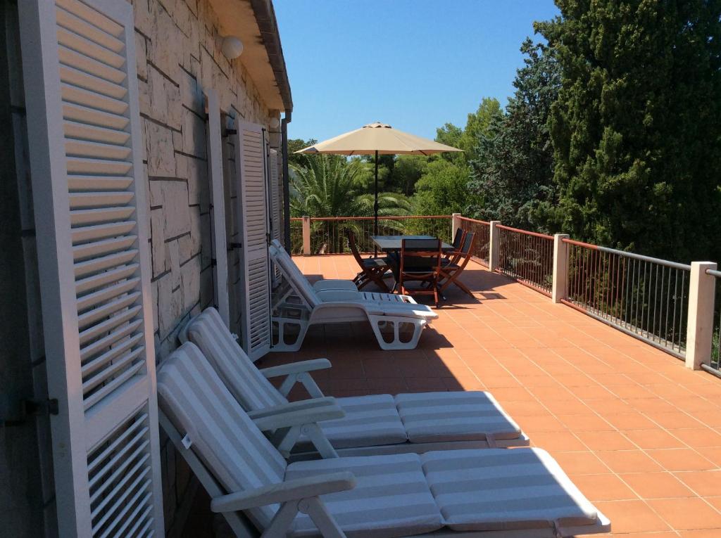 苏佩塔尔Apartment Supetar Blue Sky的庭院配有两把椅子、一张桌子和一把遮阳伞