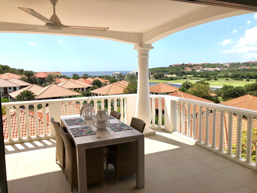 威廉斯塔德Seaview 2 Bedroom - apt40 - Blue Bay Curacao的阳台的门廊配有桌椅