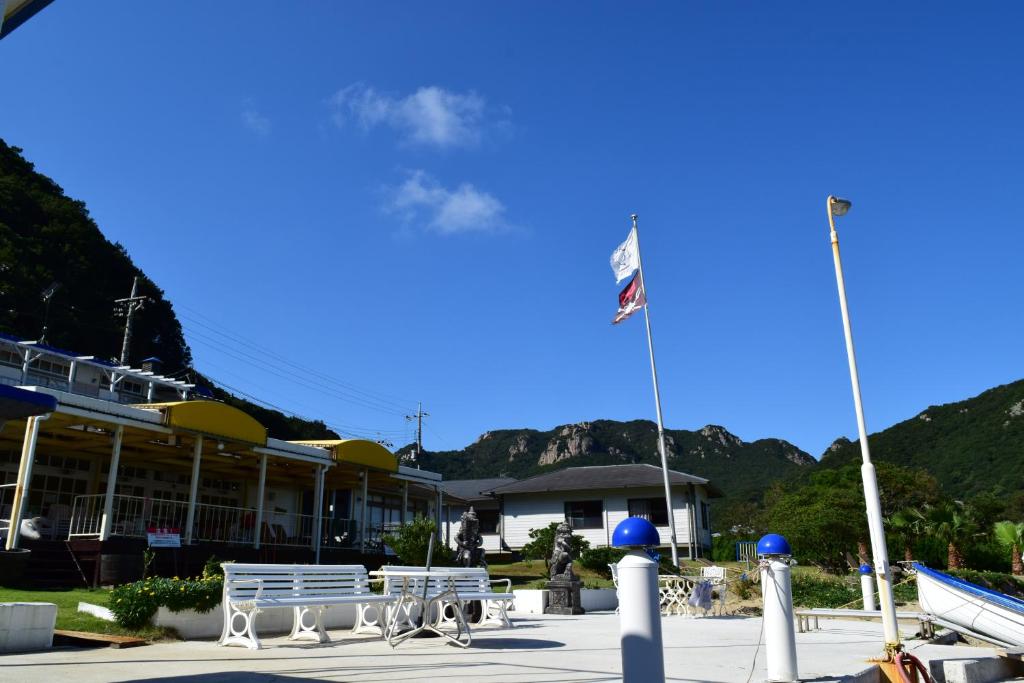 小豆岛Sea Tiger Island Inn Shodoshima的两座白色长椅,在一座有两面旗帜的建筑前