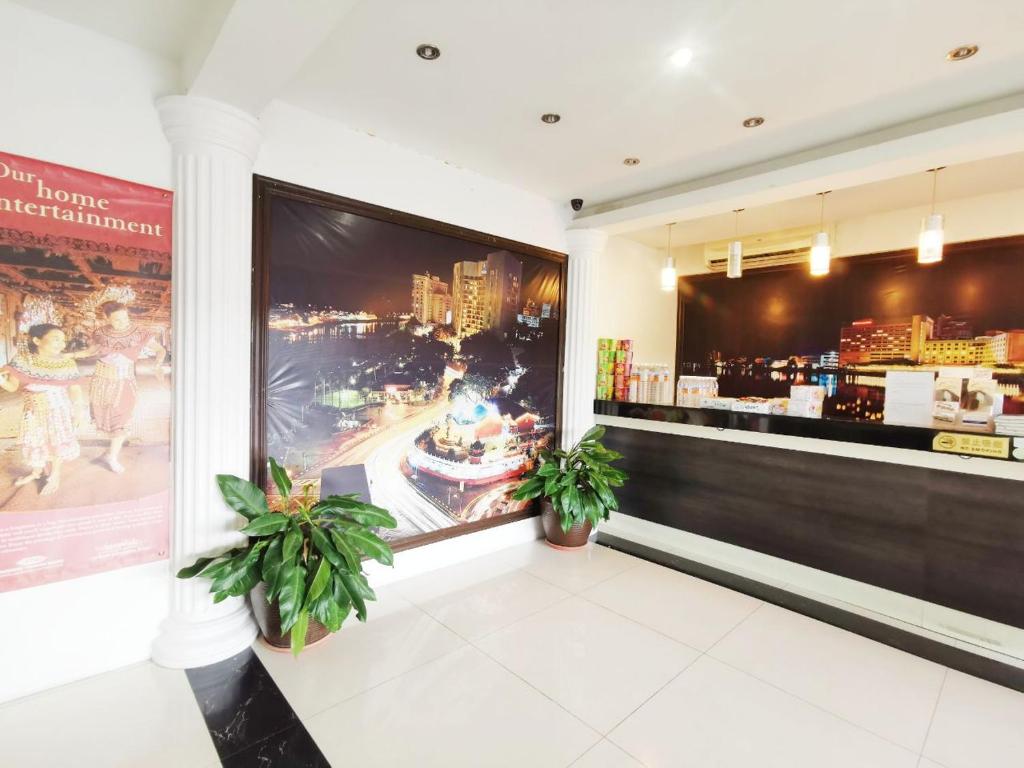 古晋Homestay Kuching Hotel的一间种有两株盆栽植物和大屏幕的餐厅