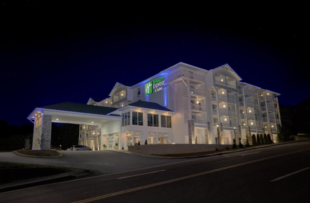鸽子谷Holiday Inn Express Pigeon Forge – Sevierville, an IHG Hotel的一座白色的大建筑,晚上有标志