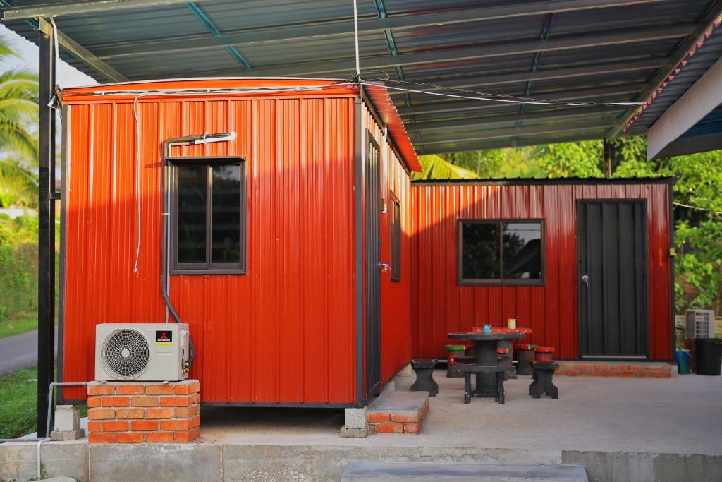 巴东勿刹Padang Besar Red Cabin Homestay的橙色集装箱,前面有桌子