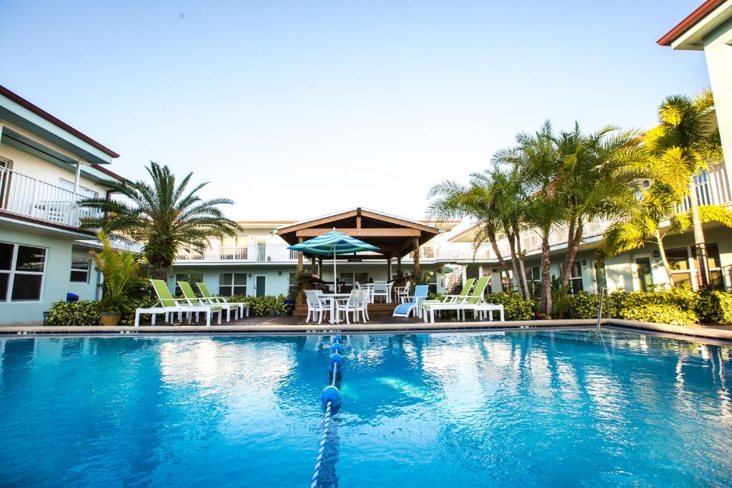 波因顿海滩桑德克海滩公寓式酒店的度假村的游泳池配有椅子和遮阳伞
