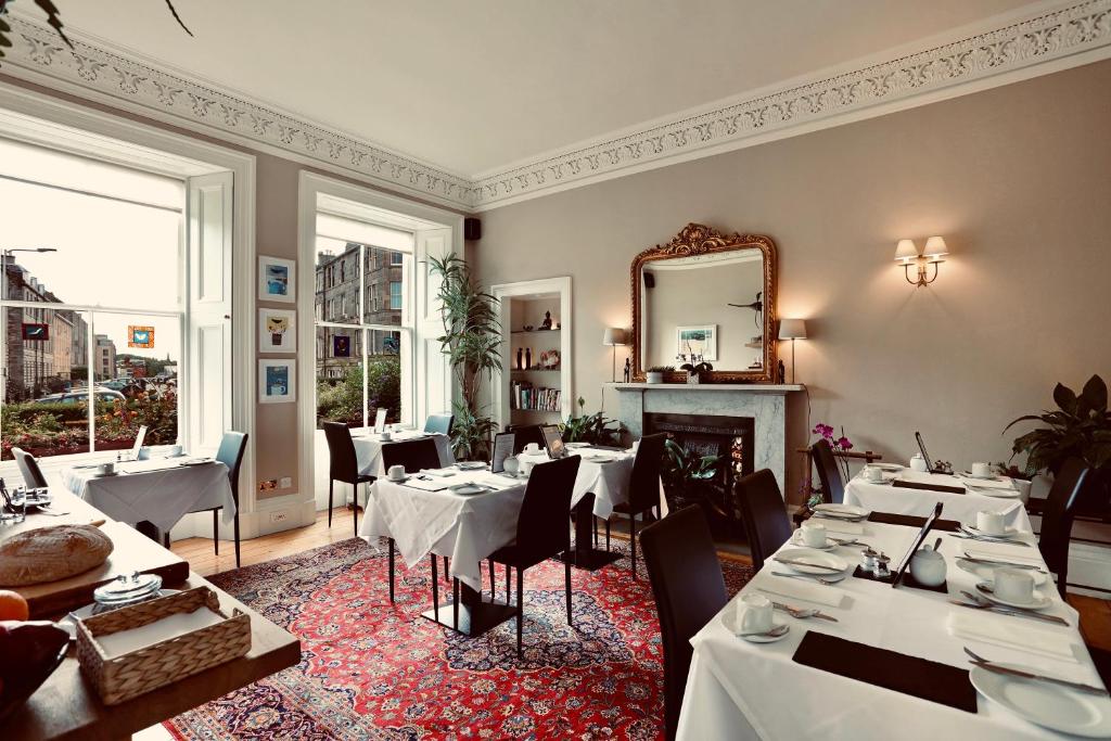 爱丁堡Sheridan Guest House的餐厅配有白色的桌椅和镜子