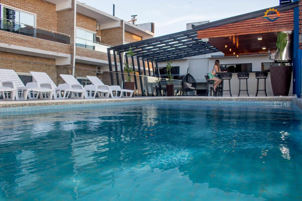 恩卡纳西翁日落酒店的一个带椅子的游泳池,一个坐在酒吧的女人