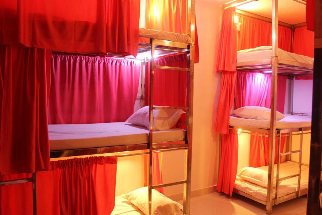 奥拉奇哈Sunset Backpackers Hostel的一间设有四张双层床和红色窗帘的房间
