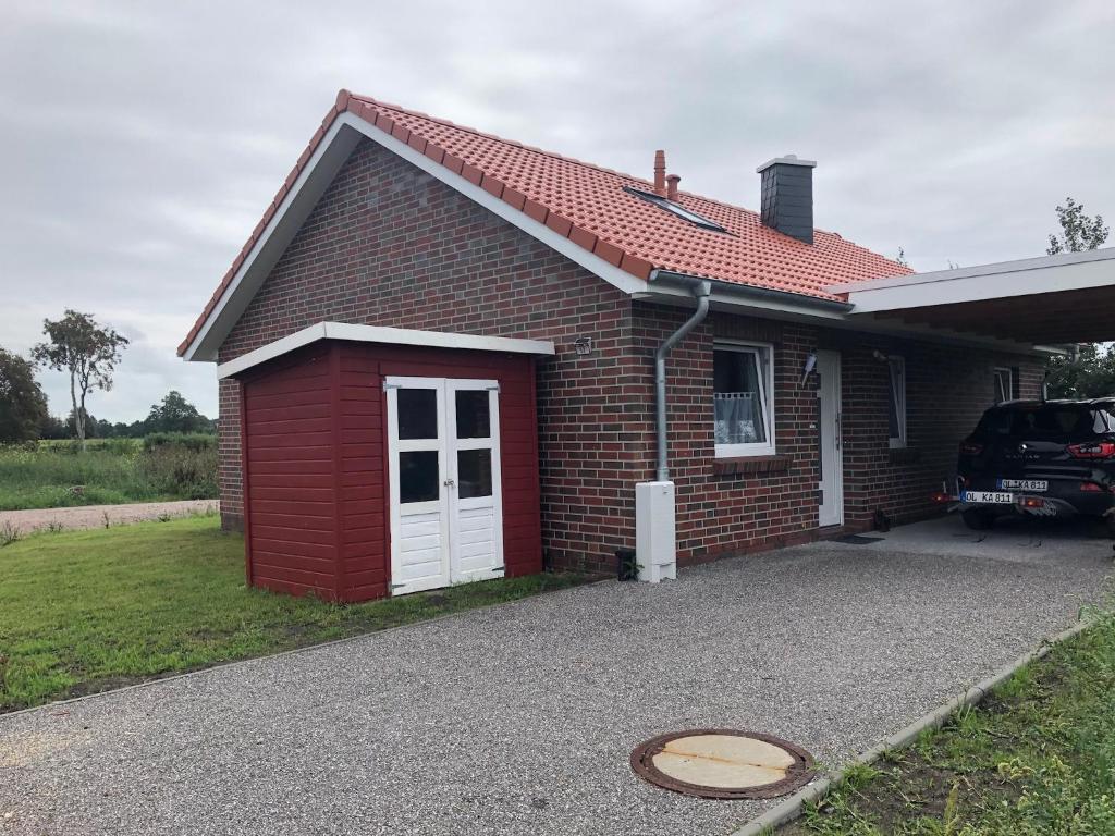SehestedtFerienhaus Wattkieker的车道上一辆红色砖房,有一辆汽车停在那里