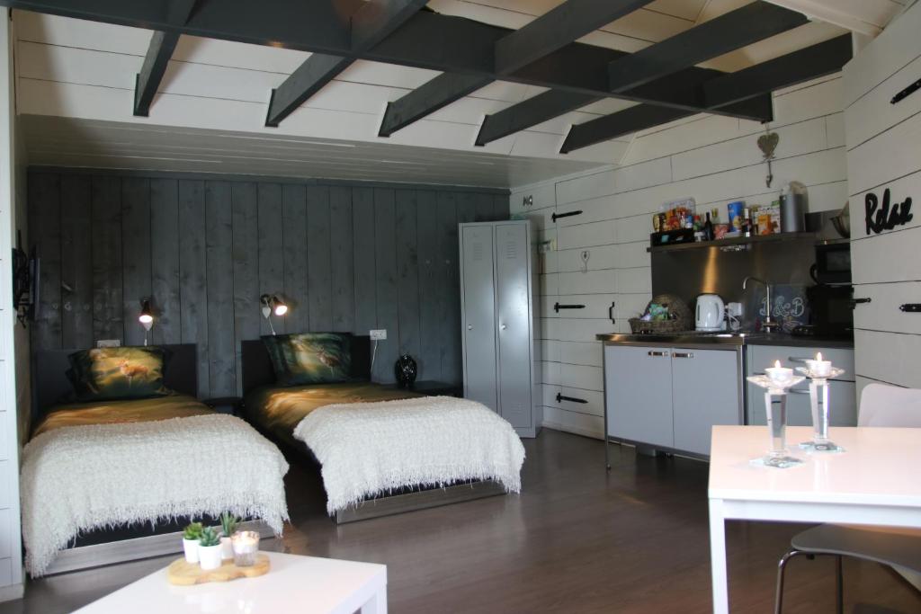 海伦多伦B&B in de Dorpsstraat的配有桌子和厨房的客房内的两张床