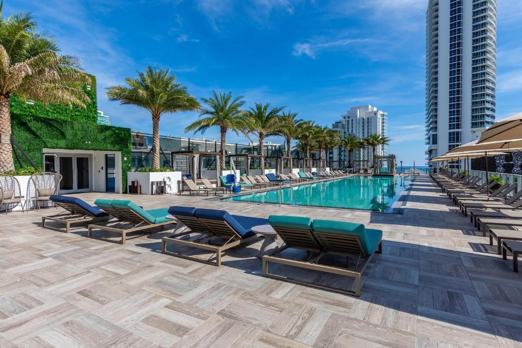 好莱坞Amazing Apartments at H Beach House的一个带躺椅和棕榈树的游泳池