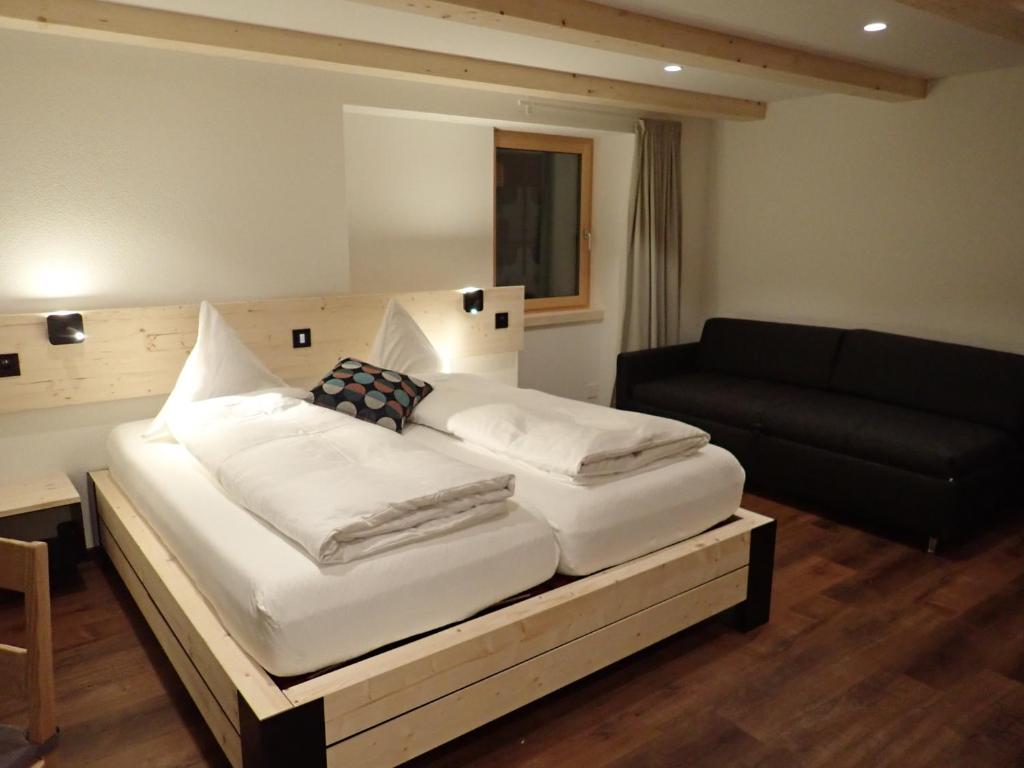 上瓦尔德富尔卡酒店的卧室配有一张白色的大床和一张沙发。