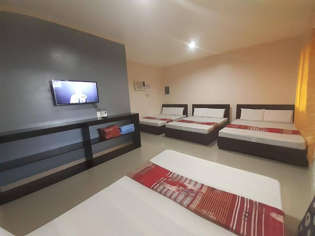 曼巴豪Veance Travellers Inn-Pabuas extension的客房设有三张床和一台平面电视。