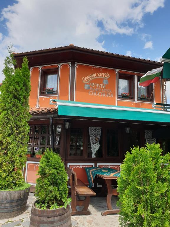 科普里夫什迪察楚楚家庭酒店的一座橙色的建筑,前面设有一张野餐桌