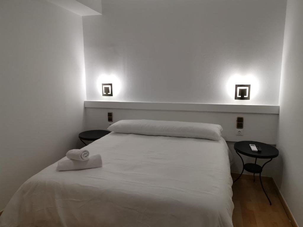 埃纳雷斯河畔圣费尔南多Hostal Quinta Santillan的一间卧室配有白色的床、两张桌子和两个灯