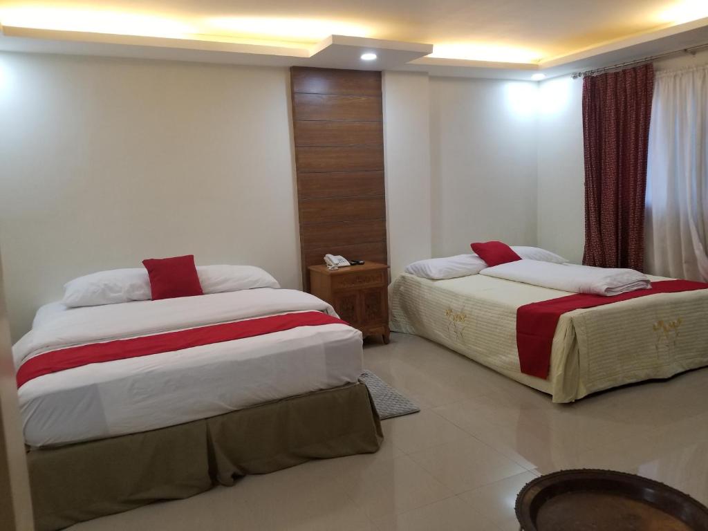 达沃市安克拉酒店的一间卧室配有两张红色和白色床单