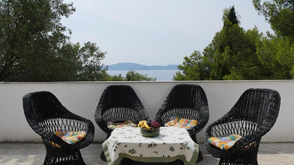 斯拉诺Apartmani Nena的庭院里配有三把椅子和一张桌子,还配有桌子