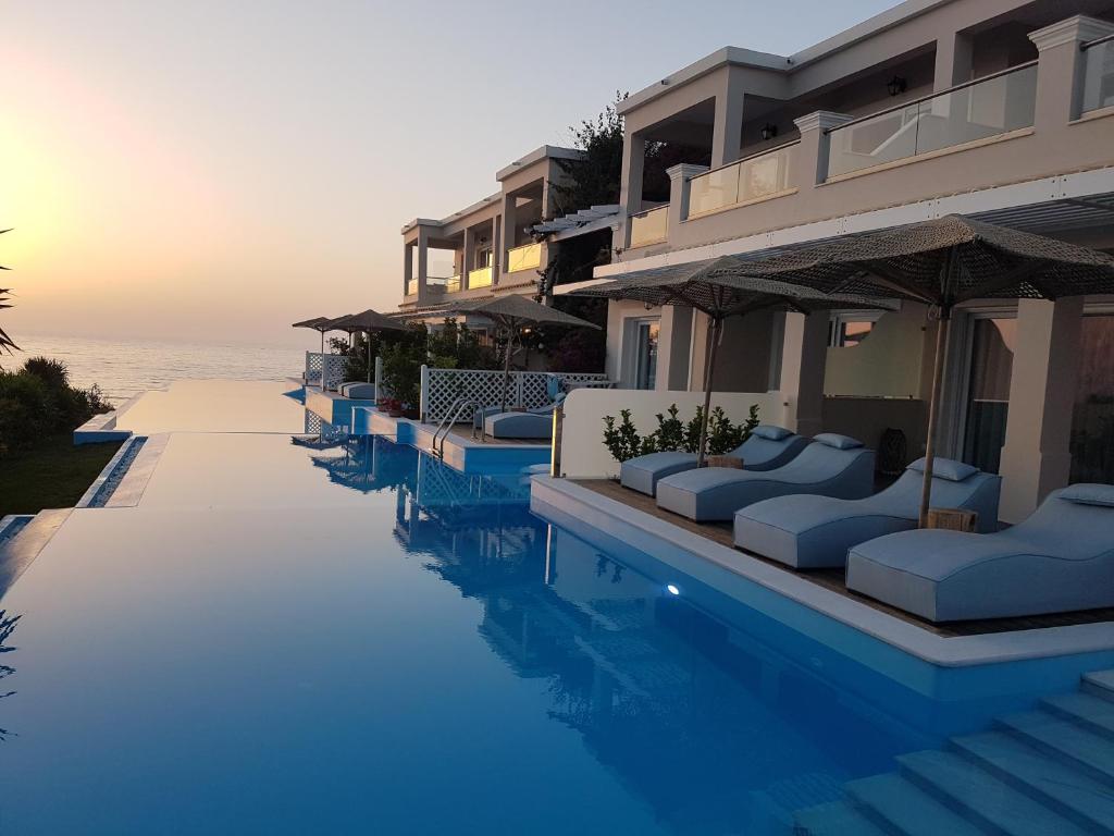 圣斯特凡诺斯帕拉利亚豪华公寓式酒店的酒店游泳池设有长沙发和海洋