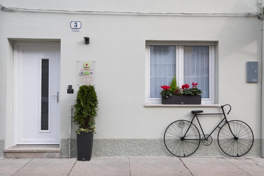 帕尔马诺瓦ZONA 30 Bike Guesthouse的一辆自行车停在白色房子前面,有两扇窗户