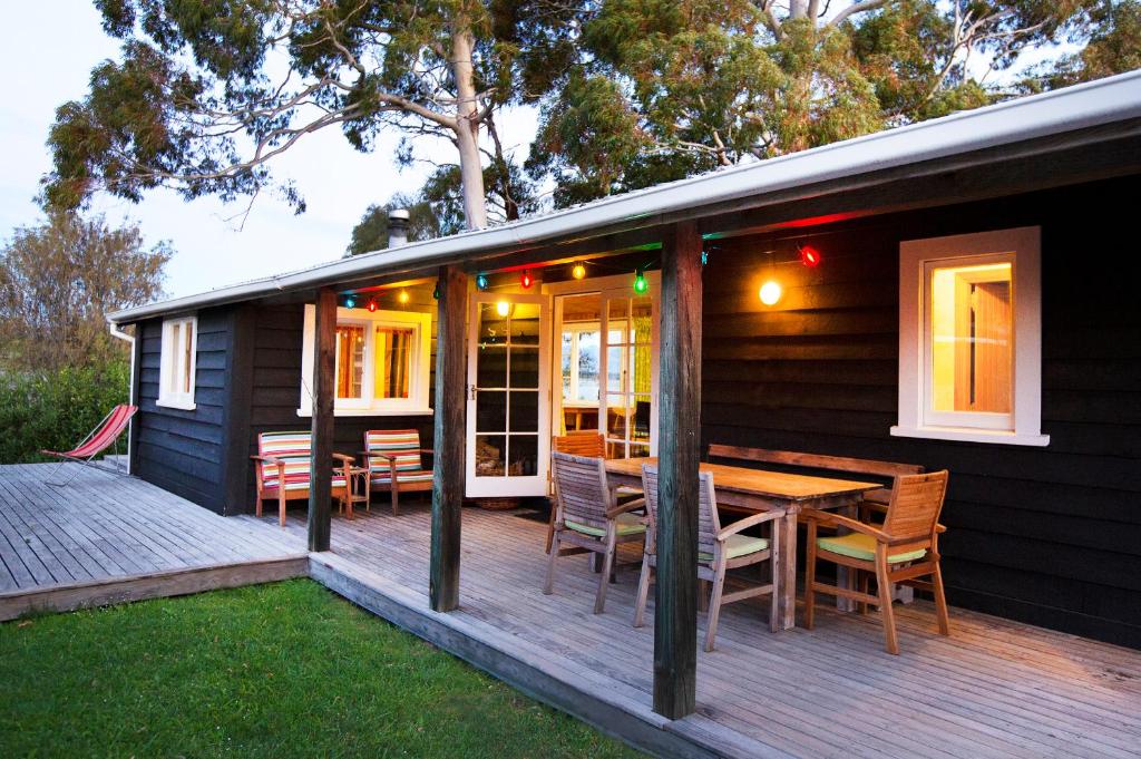 玛普瓦The Apple Pickers' Cottages at Matahua的房屋设有木甲板,配有桌椅