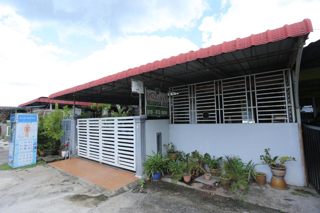 日得拉Singgahan Keluarga Jitu的白色的建筑,设有木制百叶窗和盆栽植物