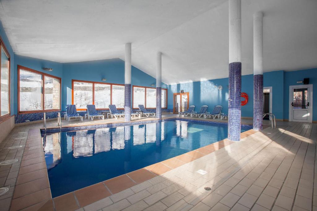 兰索尔Wuau! Apartamentos Solana de Ransol的一个带椅子和蓝色墙壁的大型游泳池