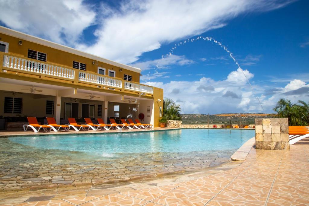 克拉伦代克Hillside Resort Bonaire的一座带椅子的建筑前的游泳池
