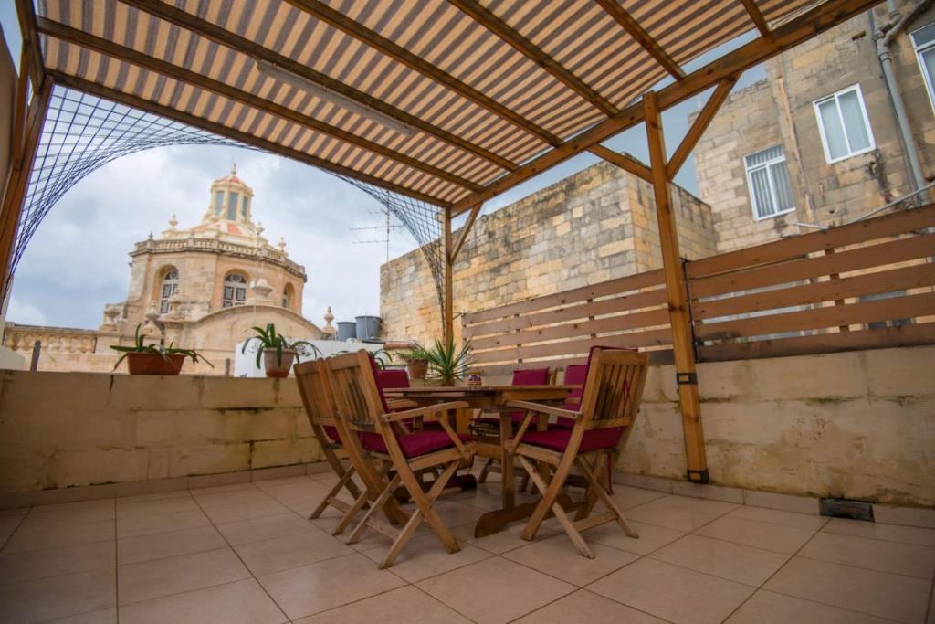 瓦莱塔Valletta Grand Central的庭院内的木桌和椅子,庭院内有一座建筑