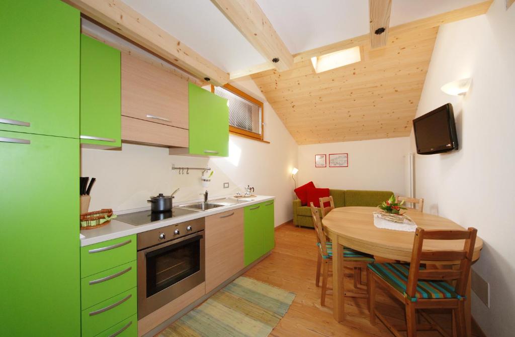 普雷达佐Casa Seler - Appartamento verde的厨房配有绿色橱柜和木桌