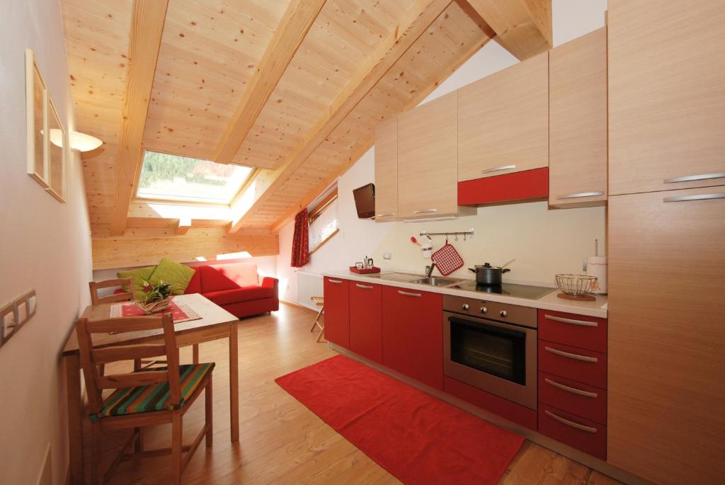 普雷达佐Casa Seler - Appartamento rosso的一间厨房,里面配有红色橱柜和一张桌子