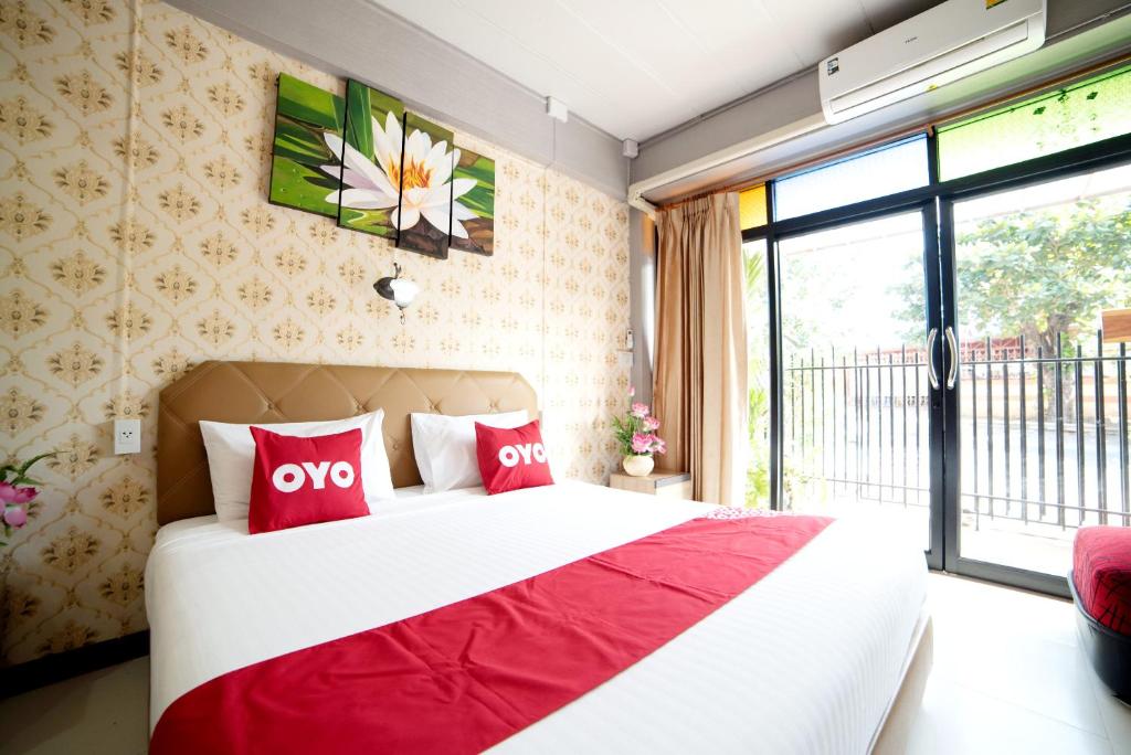 大城OYO 465 Krung Kao Traveller Lodge的一间卧室配有一张带红色枕头的大床