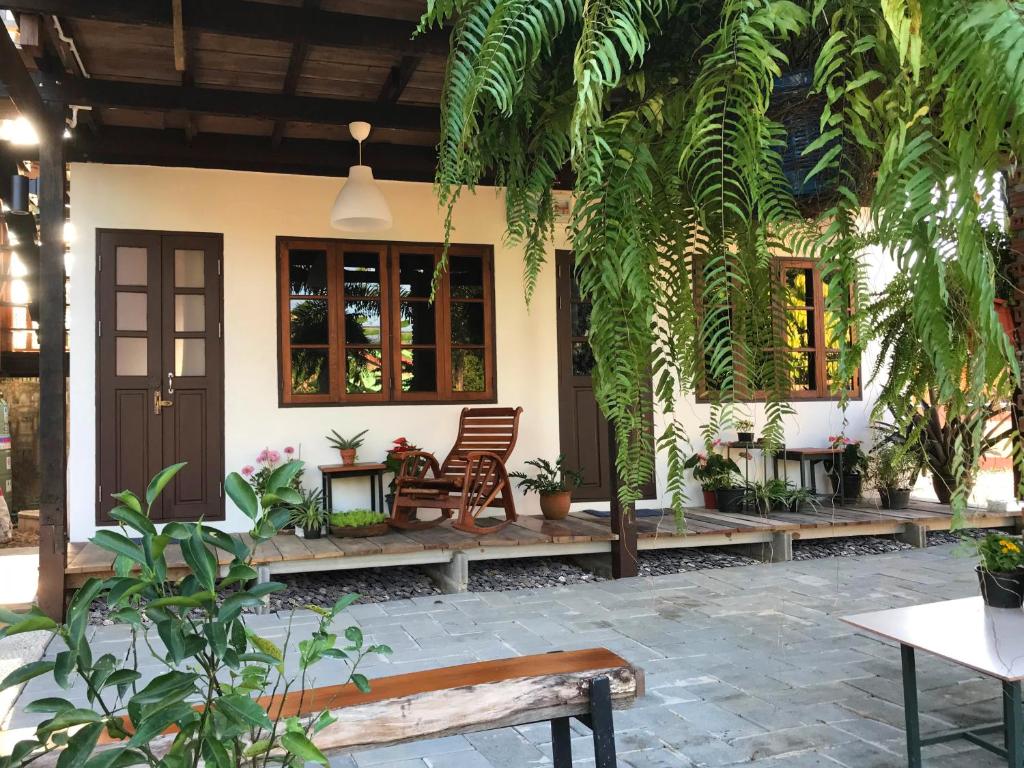 达叻府ครูหนูบ้านพัก แหลมงอบ Krunou baanpak的前面有长椅和植物的房子