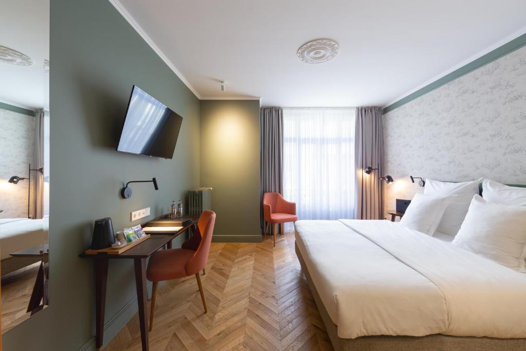 卢森堡Hotel Perrin - former Carlton的配有一张床和一张书桌的酒店客房