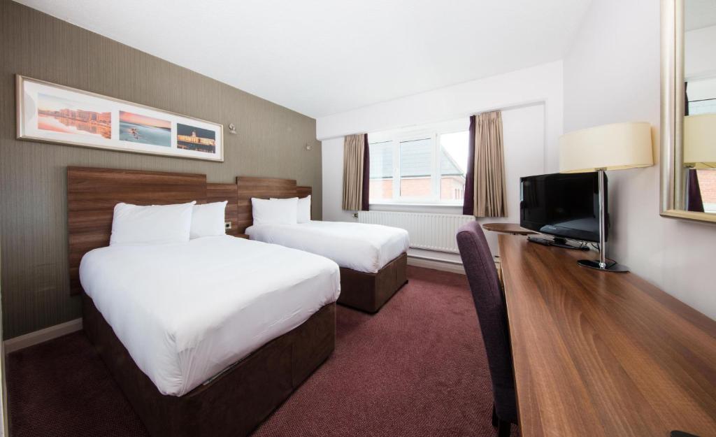 科克Leonardo Hotel Cork的酒店客房设有两张床和一台平面电视。