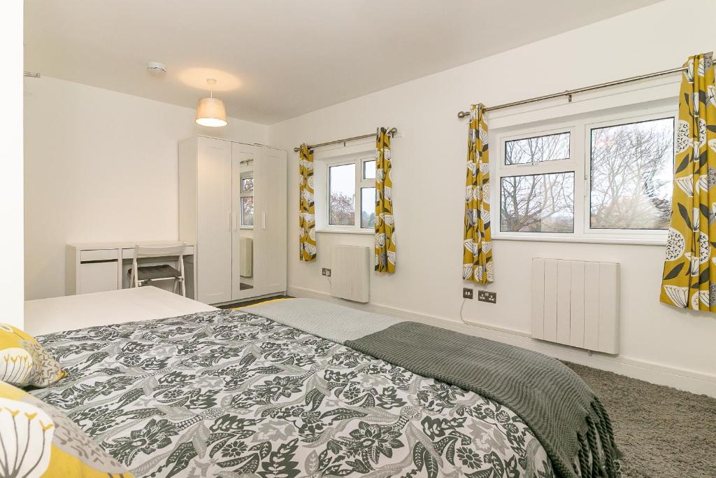 莱奇沃思Denby Lodge的一间卧室设有一张大床和两个窗户。