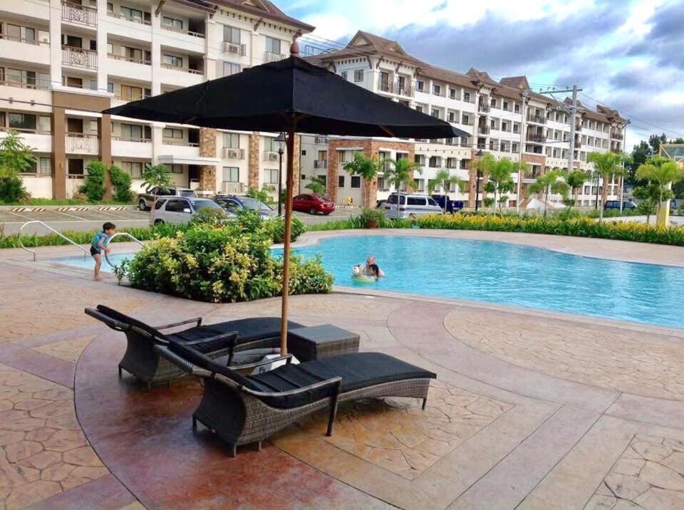 达沃市Davao 2br One Oasis Beside SM Mall-Wifi的游泳池旁的遮阳伞和躺椅
