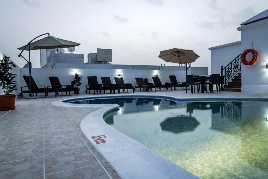 迪拜The View Al Barsha Hotel Apartments的一座大楼内的游泳池,配有椅子和遮阳伞