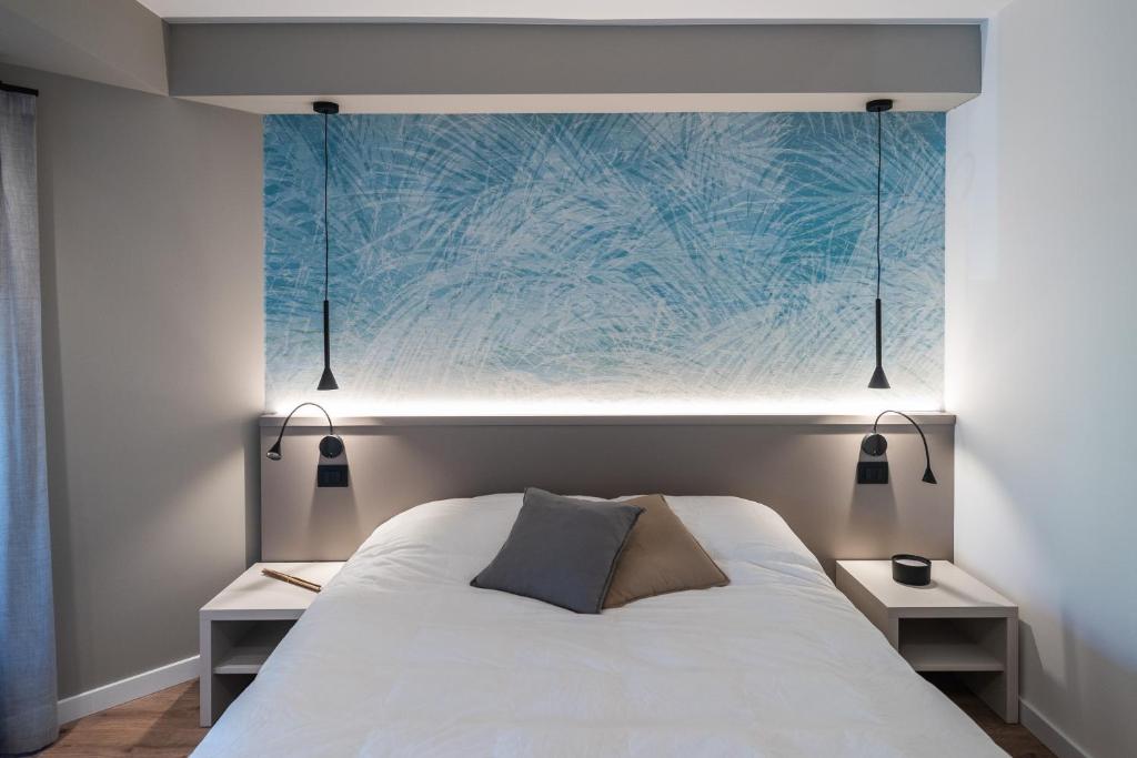 科德罗伊波Comfort Zone的一间卧室配有白色的床、两张桌子和一幅画