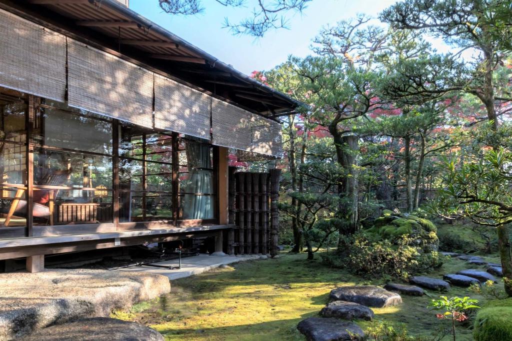 京都伝心庵 Garden Villa Denshin-An的一座花园中的建筑,前面有岩石