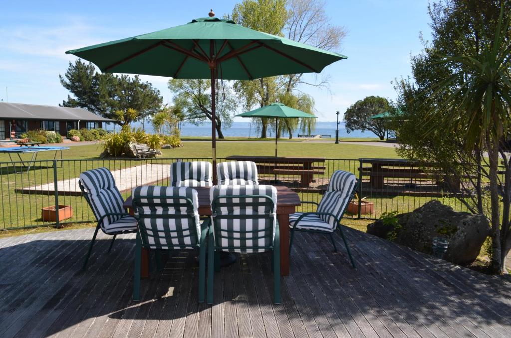 罗托鲁瓦雪松湖滨汽车旅馆和会议中心的桌椅和绿色雨伞